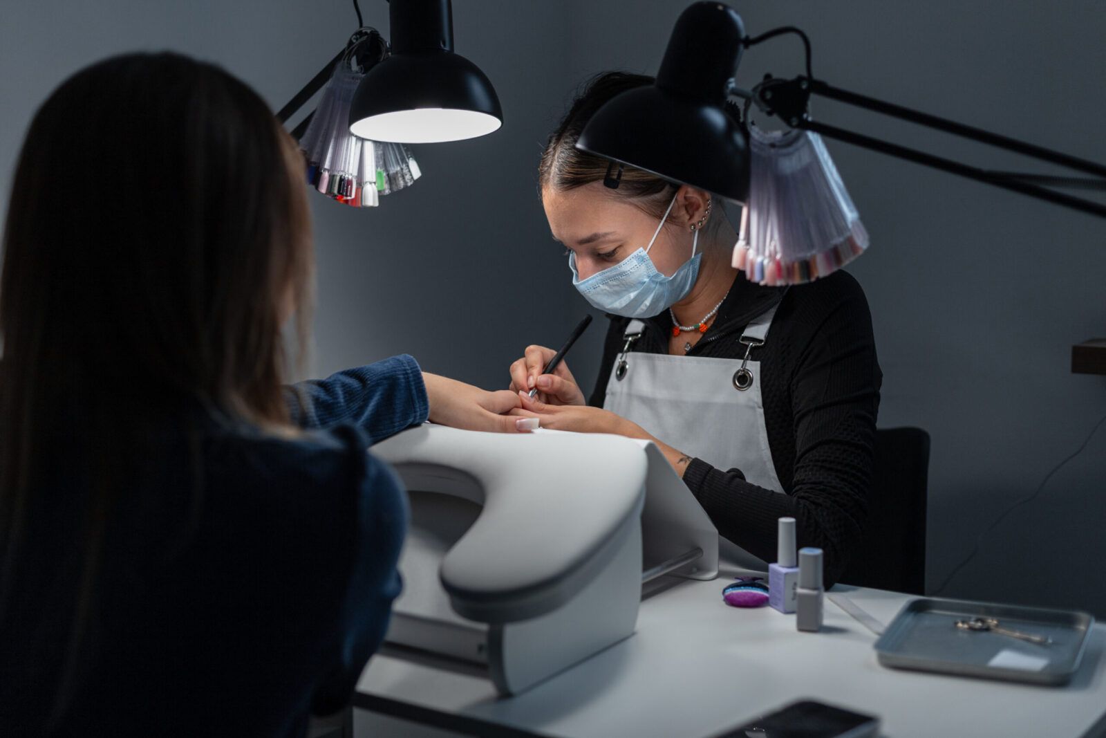 Manicurista profesional realizando manicura en salón de estética